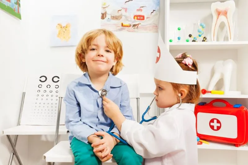 Une fille jouant au docteur examine un enfant à l'aide d'un stéthoscope