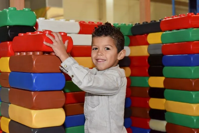 Garçon jouant au bâtisseur avec des briques lego géantes