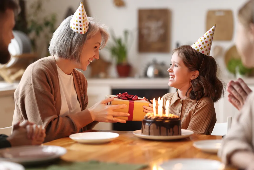 Une femme offre un cadeau d'anniversaire à une fille devant son gâteau d'anniversaire