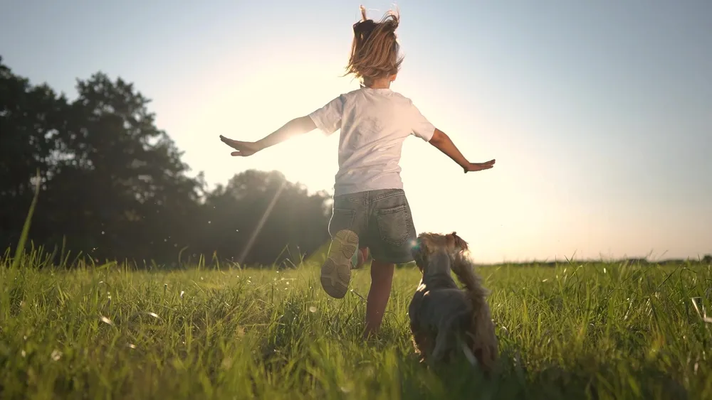 Fille courant avec son chien sur l'herbe dans un parc