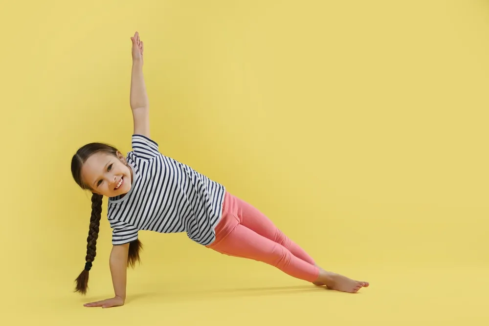 Fille faisant des exercices de gymnastique sur fond jaune