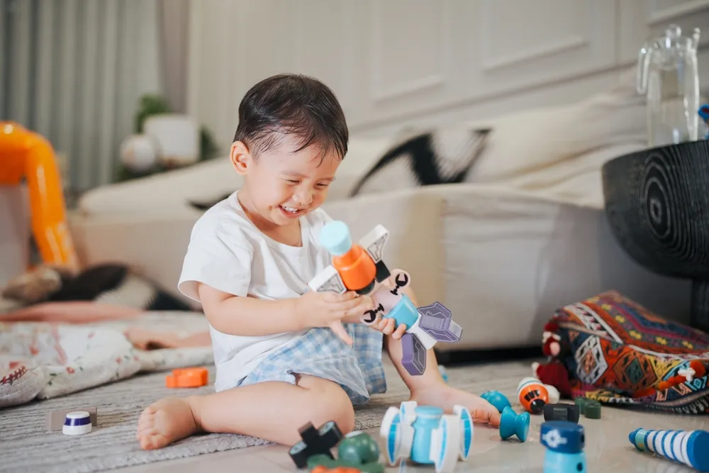 Un enfant heureux qui joue avec des jouets colorés sur le sol, souriant dans un environnement familial confortable