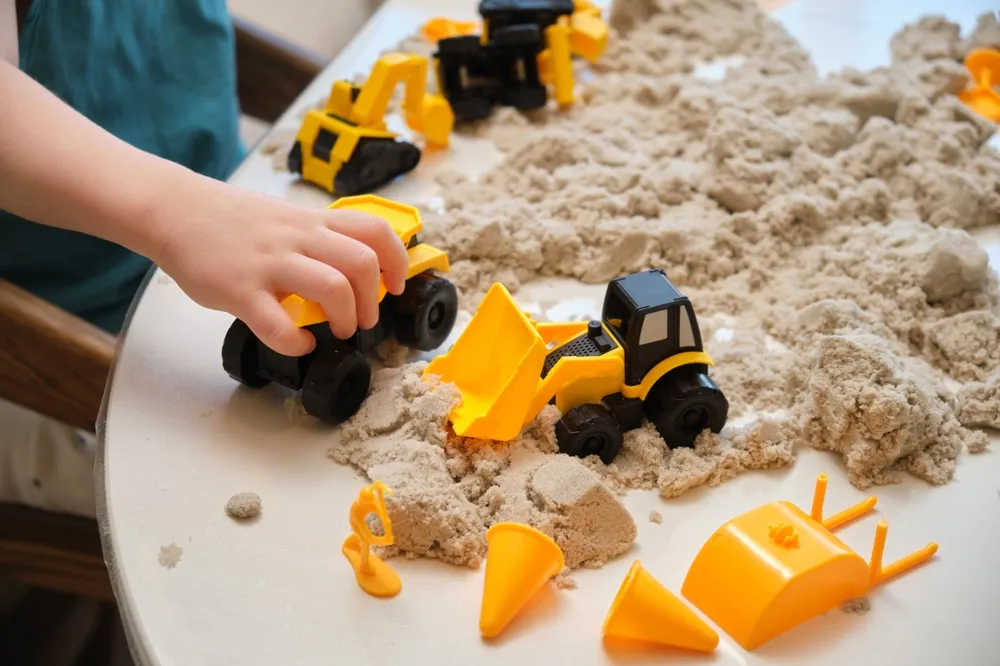 Un garçon jouant avec du sable et des camions jouets