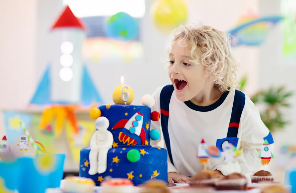 Une petite fille souriante avec son gâteau lors d'un anniversaire sur le thème de l'espace