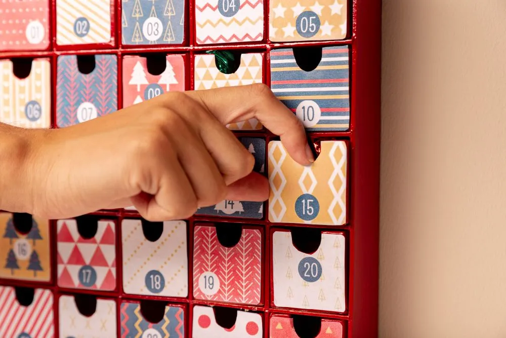 Une main ouvrant une case d'un calendrier de l'Avent