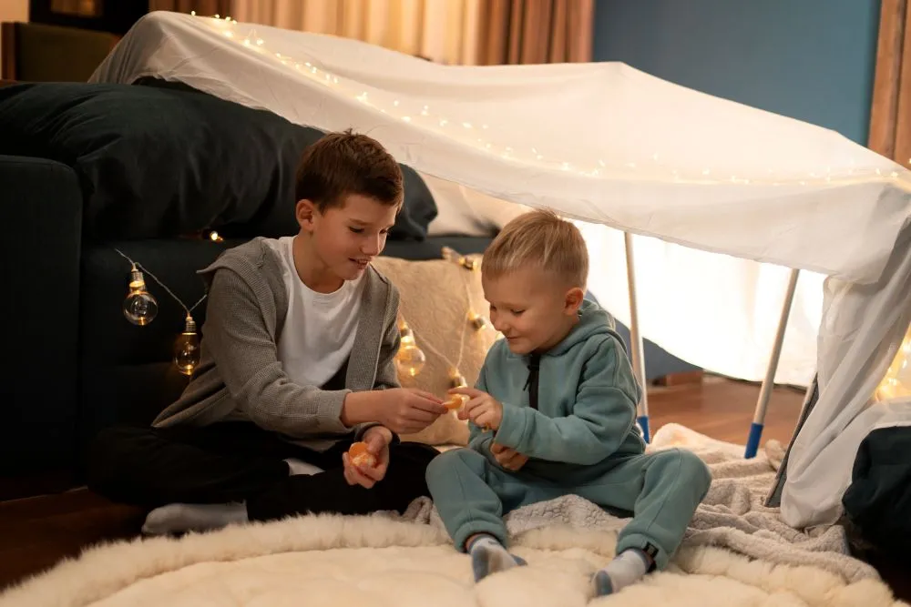 Deux enfants jouant dans une cabane faite avec des draps