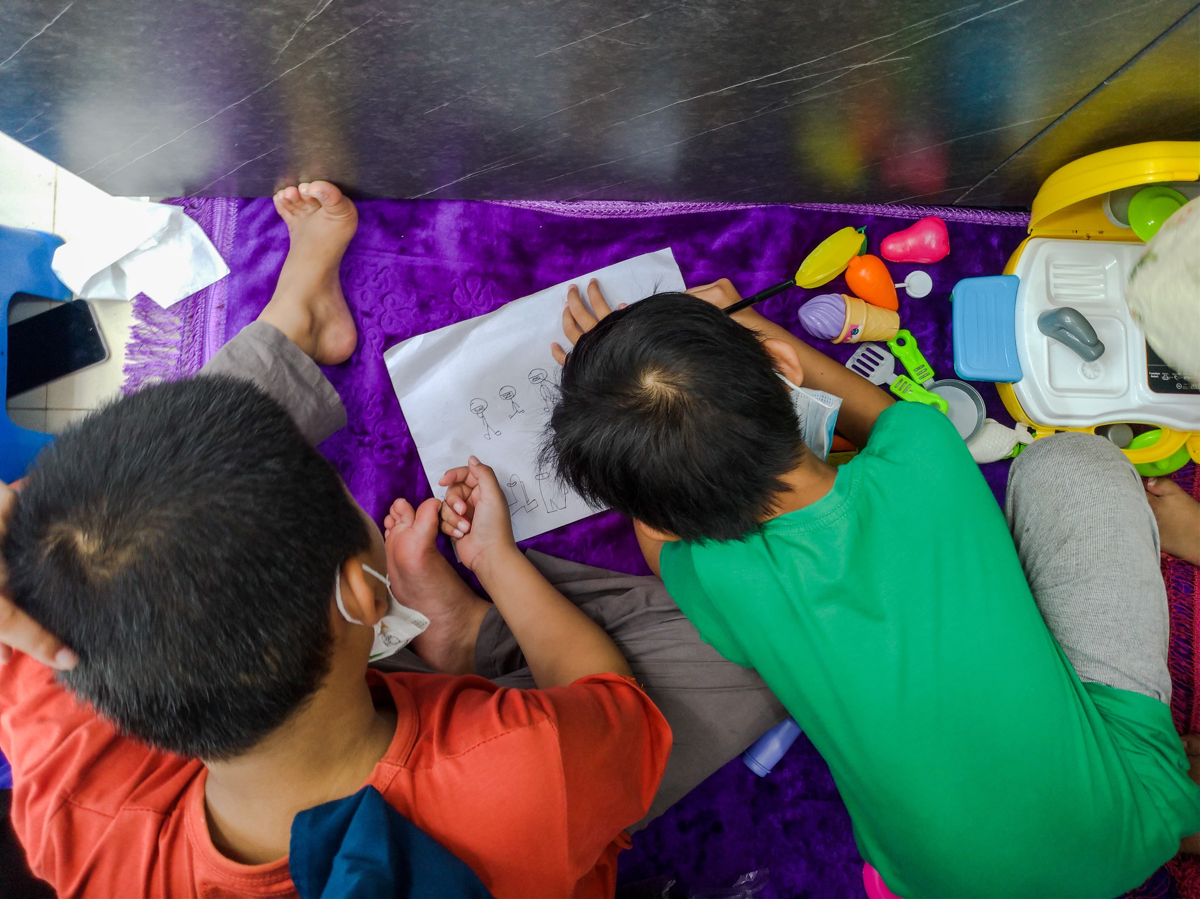 Children Draw Pictures on Floor with Toys Around